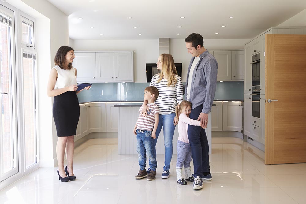 Realtor Showing Young Family Around Property For Sale Before Scheduling Home Inspection Services